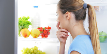 woman looking at fruits and veggies in refrigerator