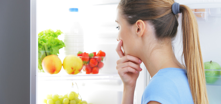 woman looking at fruits and veggies in refrigerator