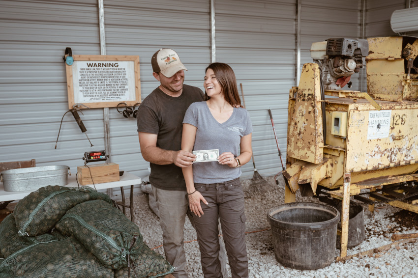 Luke and Jaime Terry of Robinson celebrate their first walnut hulling sale with their first dollar.