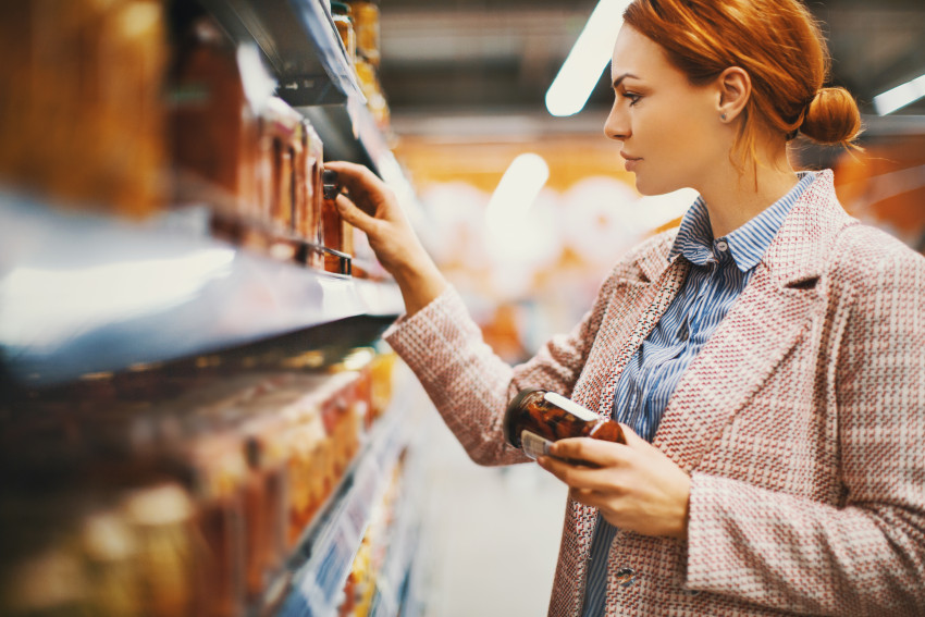 woman looks at a jar of canned vegetables