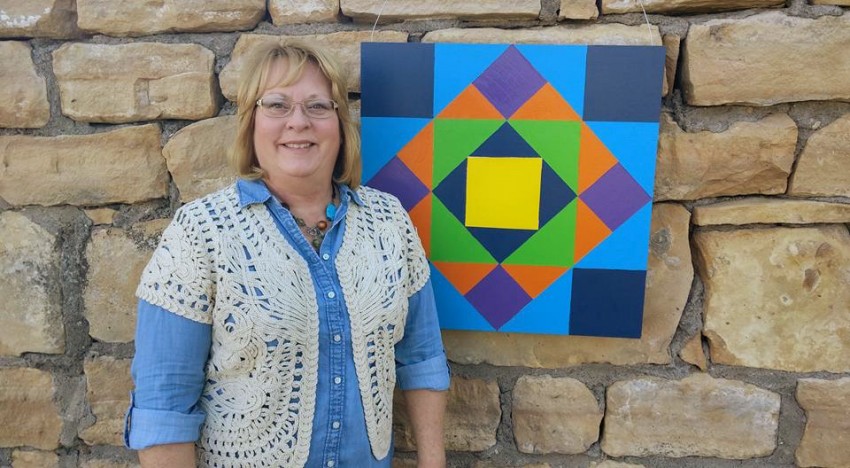 woman standing next to barn quilt